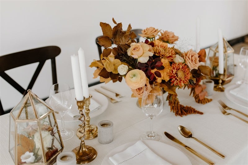 Mesa com pratos e talheres, e como decoração velas e flores